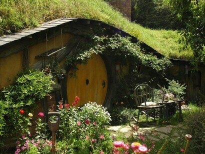Le case degli hobbit, conosciute come "smial," sono incastonate nelle colline, con porte rotonde e finestre simili a oblò che si affacciano su paesaggi verdi e rigogliosi