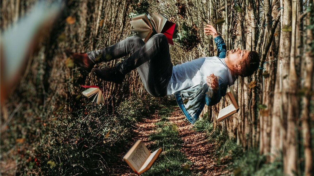 A foto de capa mostra um homem aparentemente flutuando em uma trilha de bosque, cercado por livros abertos suspensos no ar. A composição cria uma atmosfera surreal, remetendo à imaginação, ao acaso e ao poder das ideias, o que dialoga com a reflexão do artigo sobre coincidências improváveis e os limites da lógica. A imaginação muitas vezes alcança lugares onde a lógica e a estatística não conseguem chegar. Assim como na narrativa, a realidade às vezes desafia qualquer cálculo de probabilidade