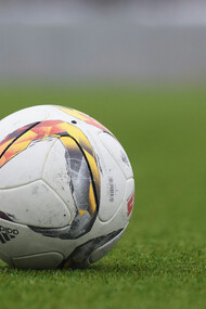 An Adidas soccer ball resting on the grass pitch, ready for the game