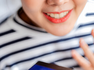 A close-up of her hand holding the screen as a cheerful woman smiles, while an AI assistant processes visual data and delivers insights, helping her organize and plan efficiently within a modern, connected lifestyle
