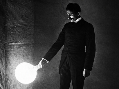 Serbian-American inventor Nikola Tesla demonstrating wireless power transmission, probably in his New York laboratory in the late 1890s. The illuminated bulb is a prototype fluorescent lamp consisting of a partially evacuated glass bulb with a single metal electrode