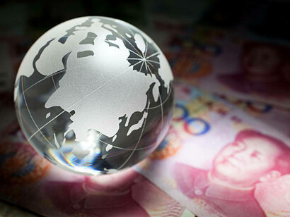 A glass globe next to Chinese yuan banknotes and coins, symbolizing global finance