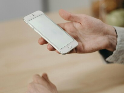 Un homme tenant son smartphone, sur le point de commencer à envoyer des SMS ou à faire défiler les réseaux sociaux