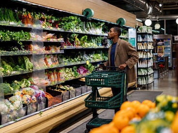 Man browsing fresh produce in a grocery store, illustrating consumer behavior and weekly shopping routines