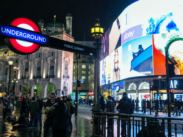 The illuminated billboards of Piccadilly Circus overlooking the crowds gathered around the iconic Eros statue in the heart of central London, UK