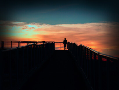 Hombre observa el atardecer desde un muelle