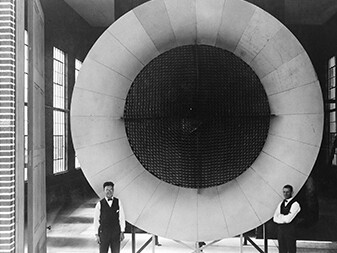 Langley's First Wind Tunnel, ca. 1920
The honeycombed, screened center of this open-circuit air intake for Langley's first wind tunnel ensured a steady, non-turbulent flow of air. Two mechanics pose near the entrance end of the actual tunnel, where air was pulled into the test section through a honeycomb arrangement to smoothen the flow. 
Courtesy NASA Langley Research Center
