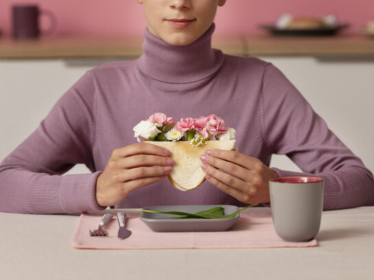 Adult seen from the front holding a sandwich filled with flowers