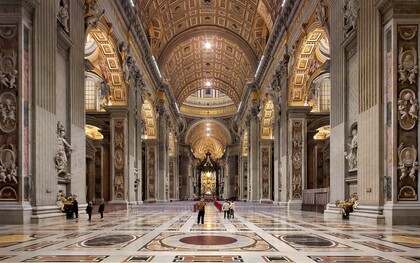 La navata centrale della Basilica di San Pietro si apre come un immenso spazio solenne e luminoso, scandito da colossali pilastri e ornato da marmi policromi e mosaici dorati, che guidano lo sguardo verso l’altare papale. Foto di Nate Bergin. Basilica di San Pietro, Città del Vaticano