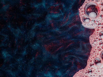 Pink foam bubbles creating a contrast against the dark water's surface