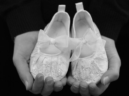 Mutter hält ein Paar blaue Babyschuhe mit goldenen Quasten