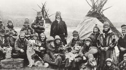 Nordic Sámi people in Sápmi (Lapland) gathered in front of two traditional Lavvu tents, showcasing their nomadic lifestyle that has endured for centuries across the vast northern landscapes of Norway and Sweden