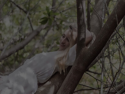 A young woman gracefully lounges on a tree trunk, embodying a sense of serenity and natural beauty