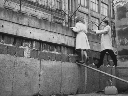 Una pareja de Berlín Occidental hablando con familiares en un edificio de apartamentos de Berlín Oriental sobre el Muro de Berlín