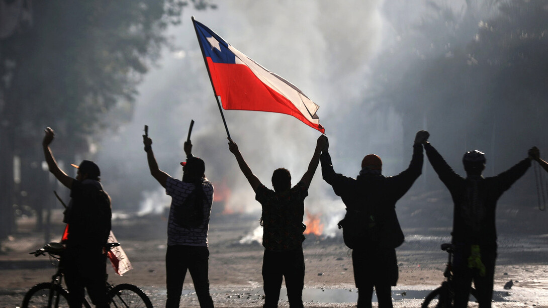 Grupo de 5 hombres con la bandera de Chile durante el 'Estallido social' que comenzó en el año 2019