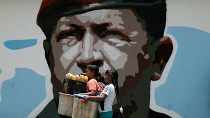 Dos jóvenes pasan delante de un mural que recuerda a Chávez en Caracas
