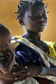Young girl tenderly holding a baby in Mozambique, evoking poverty in a setting