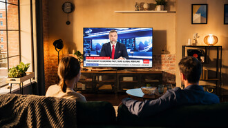 Young couple watching the latest news on television in a cozy loft apartment