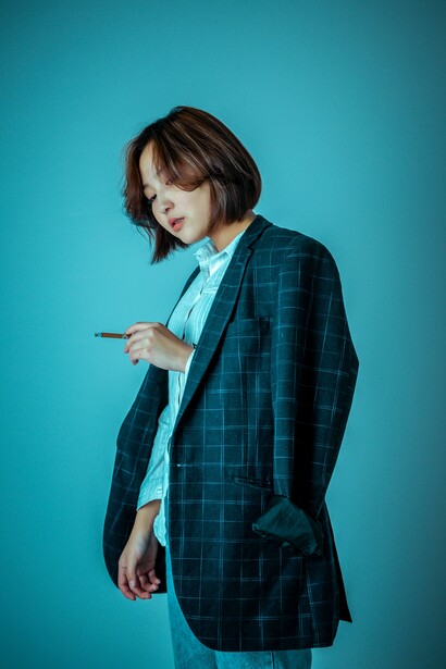 A person in a blue blazer holding a cigarette 