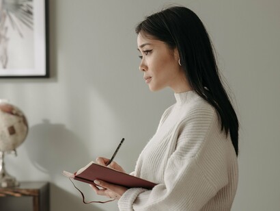 A woman pausing mid-sentence with pen in hand, representing the quiet acceptance that not every question has an answer