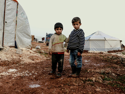 Young boys standing in a refugee campsite in Syria, capturing the human impact of conflict and displacement