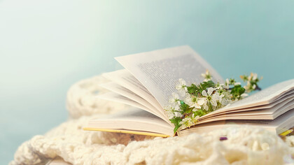 Flores sobre un libro abierto representando a la poesía, la cual, en virtud de su forma agradable tanto al oído como al entendimiento, facilita la transmisión de una doctrina ardua y abstracta como la filosofía