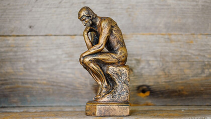 The 'Thinking Man' statue portrays a deeply reflective individual, poised in contemplation