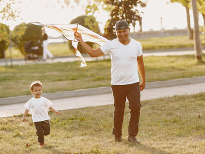 Father and son giggling and enjoying themselves while flying a kite together