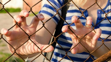 Una joven atrapada detrás de una reja