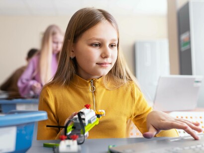 Una bambina sta usando un computer per un'attività di costruzione con parti elettroniche