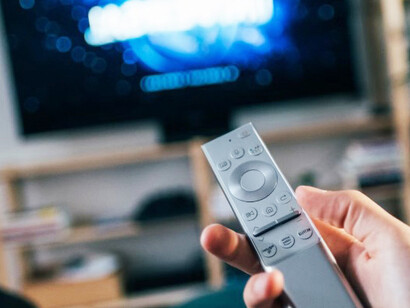 A person with a black remote control, exploring seamless platforms for entertainment