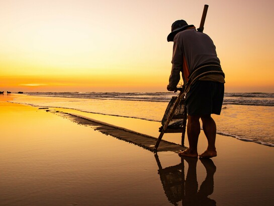 A solitary fisherman working along the water's edge at sunrise, symbolising the humble labour that replaced a future once imagined on the stage
