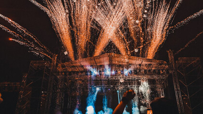 The crowd comes alive under the lights, hands in the air, fully immersed in the energy of the night