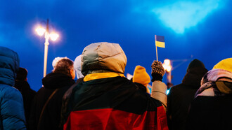 Ciudadano alza una pequeña bandera de Ucrania en una manifestación en contra del conflicto bélico con Rusia