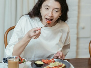 Woman eating a meal with a fork and knife during breakfast