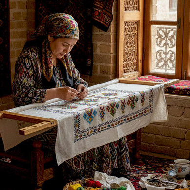 An Uzbek master craftswoman meticulously works on a suzani-style tablecloth, preserving the ancient art of hand embroidery