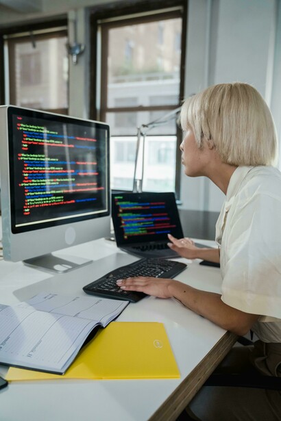 Mulher programadora concentrada em atividades de software no escritório trabalha diante de um computador. A presença feminina nas áreas de inteligência artificial e tecnologia ainda permanece abaixo da dos homens. A diversidade nas equipes técnicas é considerada fundamental para reduzir vieses nos sistemas digitais. O artigo destaca a importância de ampliar a participação das mulheres na construção da IA