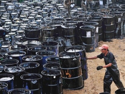 Operario manejando barriles de petróleo