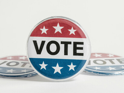 Several ''Vote'' pins against a white background