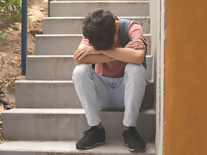 Encounter the evocative sight of a solemn boy seated on stairs, offering a front-view glimpse into the depths of sorrow and introspection