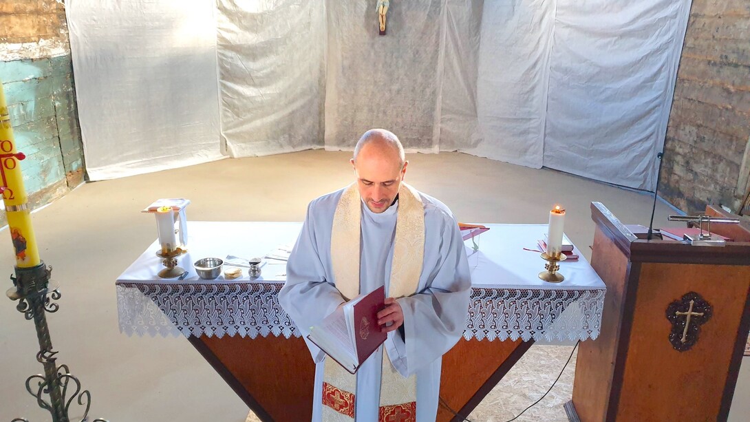 Padre em pé frente à igreja