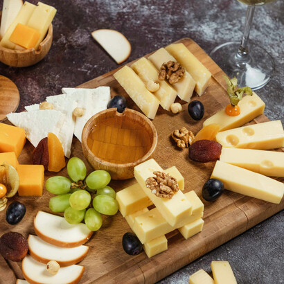 Overhead food photography of cheese dipped in honey, rustic snack platter with white wine pairing