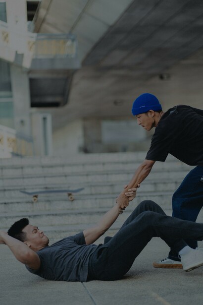 Homem asiático dando a mão ao amigo caído