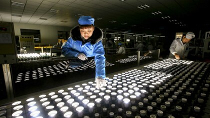 Empleados chinos trabajando en una línea de producción de bombillas de bajo consumo

