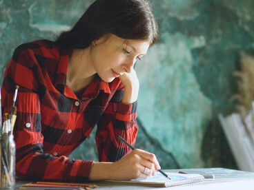 A woman focused on drawing in her sketchbook