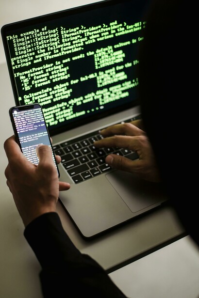 Anonymous figure with phone and laptop representing the risks to privacy and fairness in today’s data-driven world