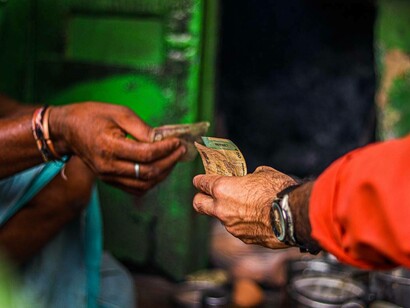 Scambio di denaro in contanti tra due persone, simbolo di una transazione economica diretta e quotidiana