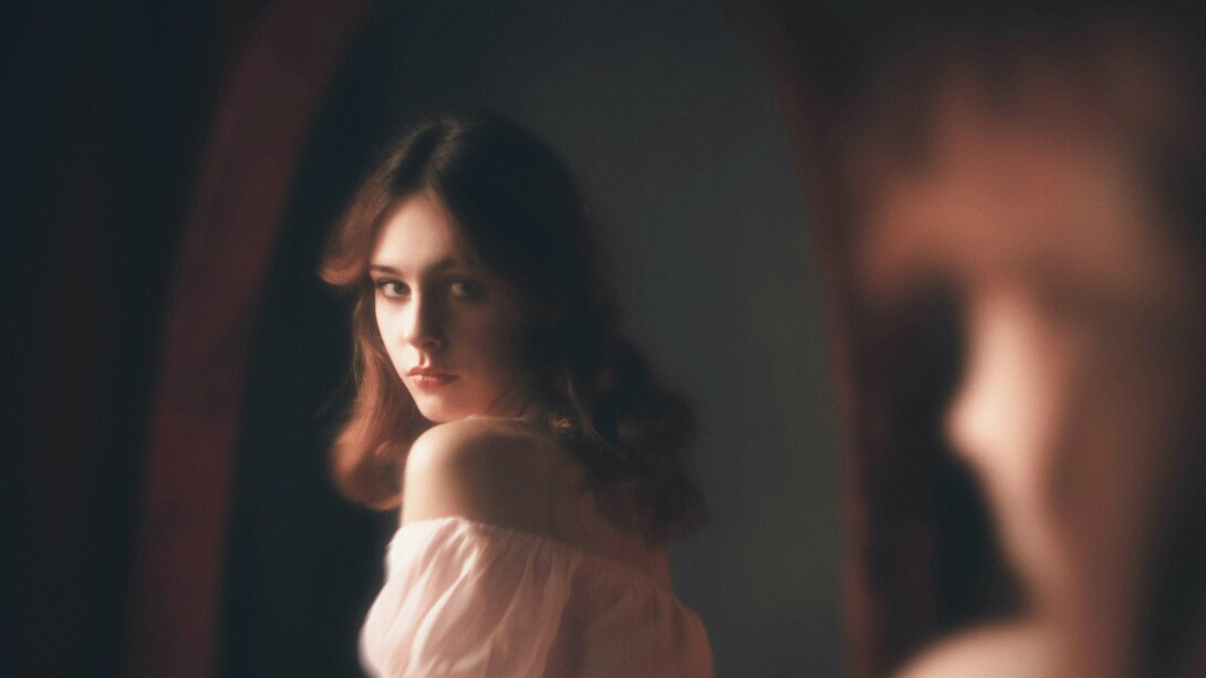 A woman looking at her reflection, representing the curiosity about one's appearance that always exists
