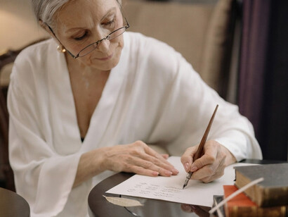 An elegant senior woman carefully writes a handwritten letter in the quiet surroundings of her home