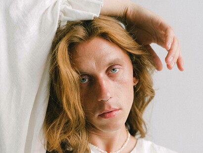 A transgender man with arm over head posing for the camera